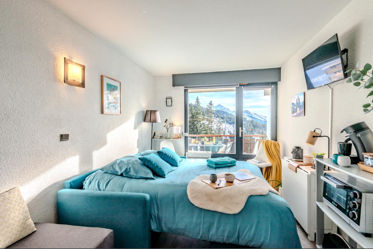 Bedroom with teal bed and mountain view through the bay window