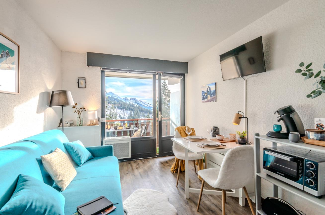 Living room with turquoise sofa, dining table and television